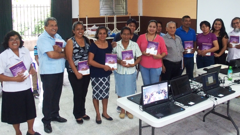 Adult learners in El Salvador display their books for their VLCFF course.